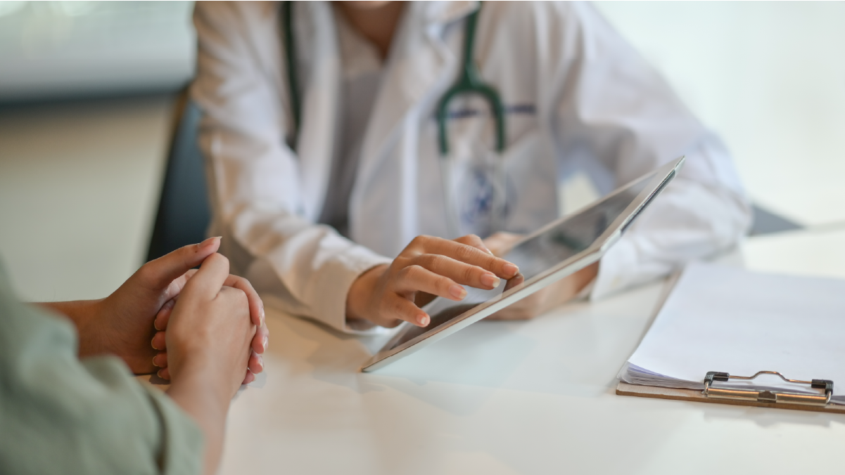 A doctor talking to his patient while informing her about something on his tablet