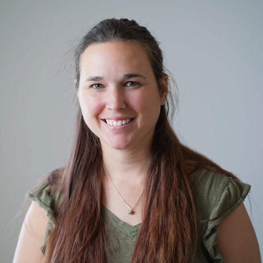 Professional headshot of a smiling woman with long brown hair