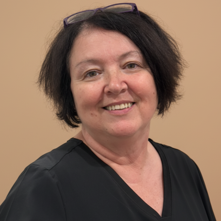 A formal portrait of a women in a black top and with glasses on her head.